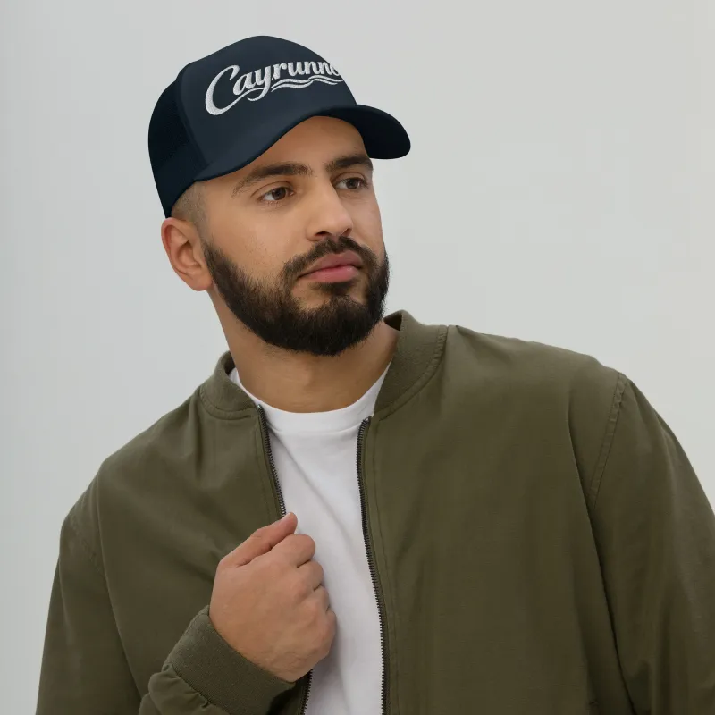 Man wearing Cayrunner Coastal Signature Trucker Cap in navy with embroidered logo, paired with olive jacket