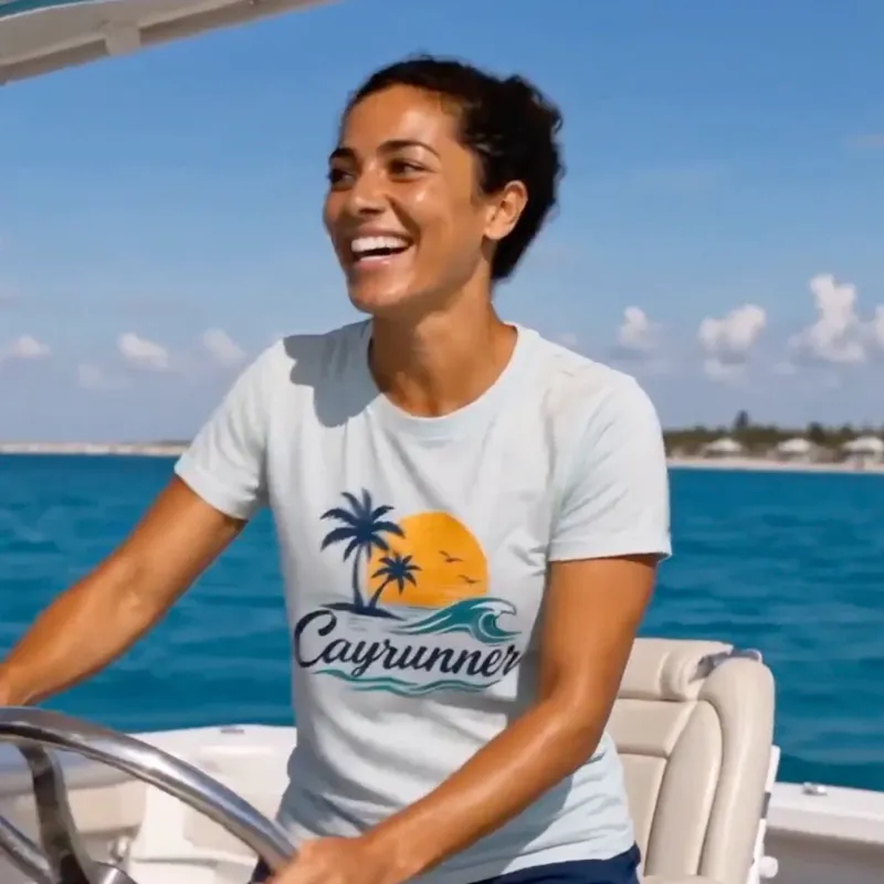 Woman driving a boat wearing the Cayrunner Sunset Break Unisex T-Shirt in athletic heather with palm tree sunset design