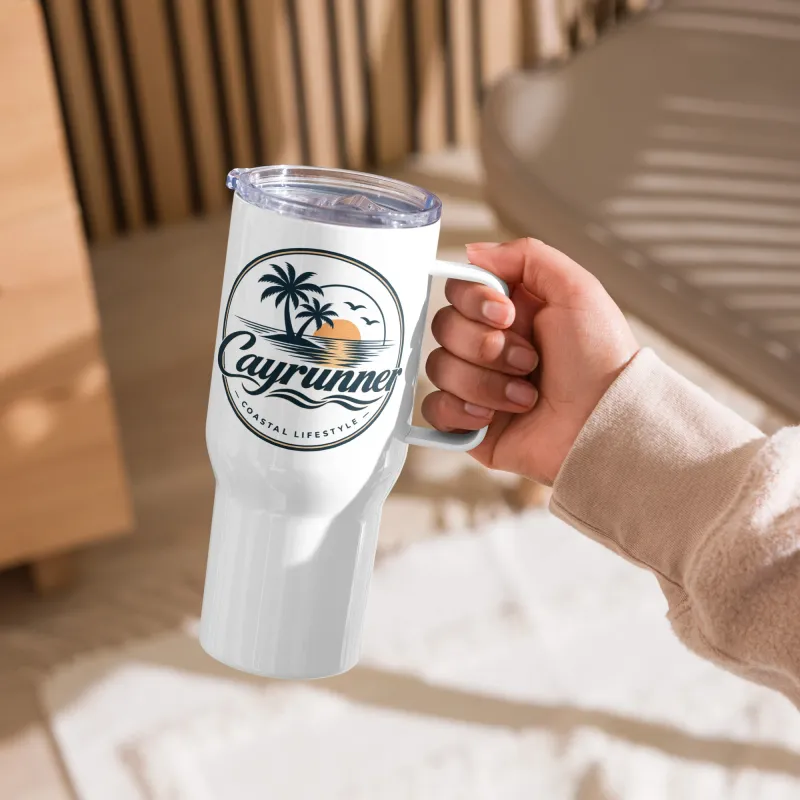 Hand holding white Cayrunner Sunset Run Travel Mug with Handle, showing palm tree coastal lifestyle logo up close.
