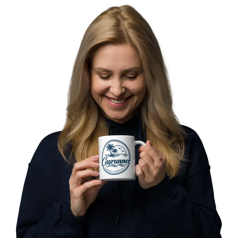 Woman smiling while holding Cayrunner Coastal Signature Coffee Mug, showing palm tree coastal lifestyle logo.