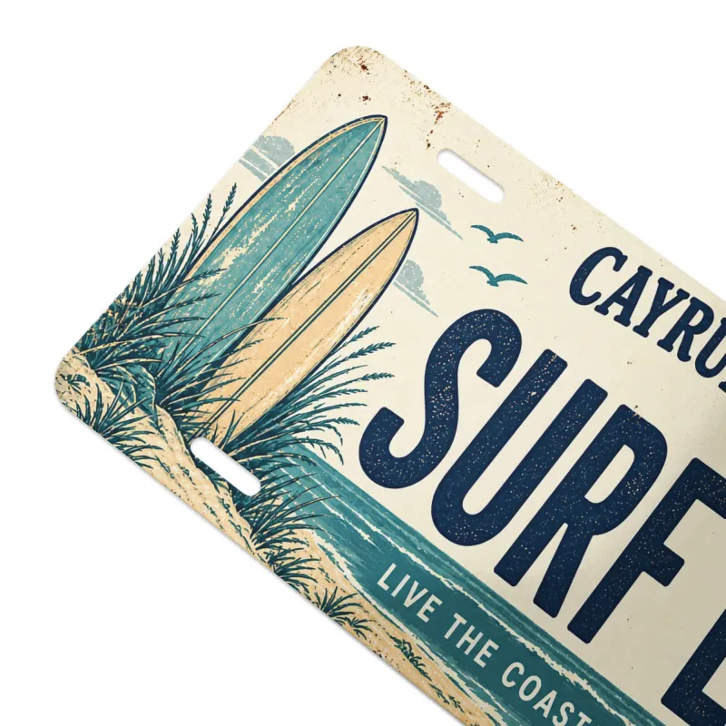 Close-up angled view of Cayrunner Surf Life Vanity License Plate, showing surfboards and beach grass artwork.