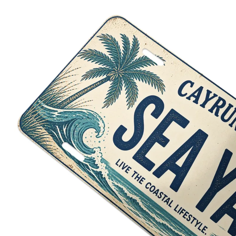 Close-up angled view of Cayrunner Sea Ya Vanity License Plate, showing palm tree and ocean wave artwork.
