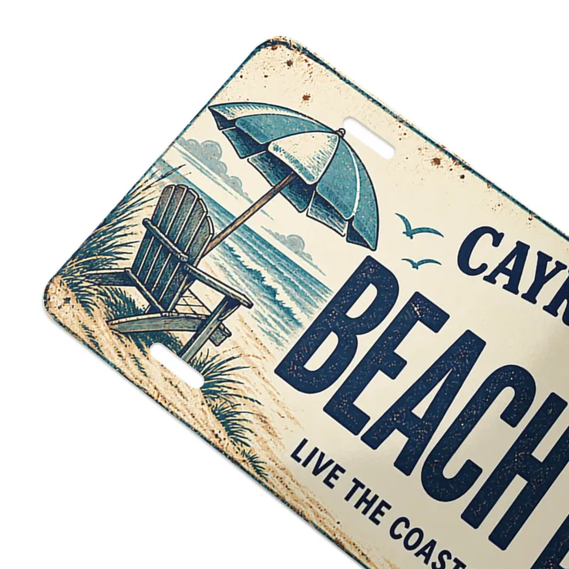 Close-up angled view of Cayrunner Beach Bum Vanity License Plate, showing rustic beach chair and umbrella artwork.