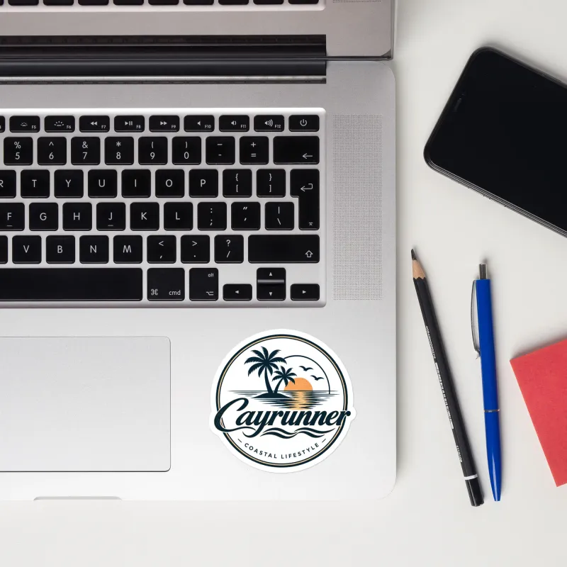 Cayrunner Sunset Run Sticker, 3 inch, applied to a laptop, showing palm tree and sunset coastal lifestyle logo.