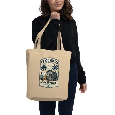 Woman carrying the Cayrunner Chase Swells organic cotton tote bag with surf shop and palm tree badge design
