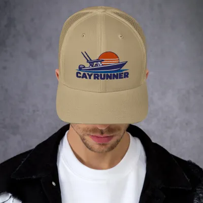Man wearing the khaki Cayrunner Boat Sunset Logo Trucker Cap with embroidered center-console boat and sunset design
