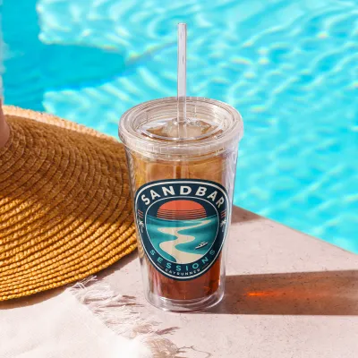Sandbar Sessions Cayrunner Badge Clear Plastic Tumbler with an iced drink beside a pool and a straw hat