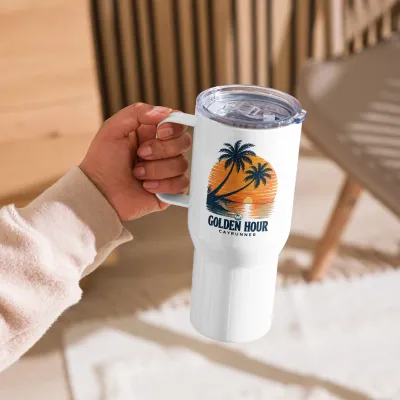 Cayrunner Golden Hour Tropical Sunset Travel Mug with Handle, held by the handle in a sunlit room