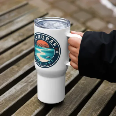 Sandbar Sessions Cayrunner Badge Sunset Travel Mug with Handle, held by the handle on a wooden bench