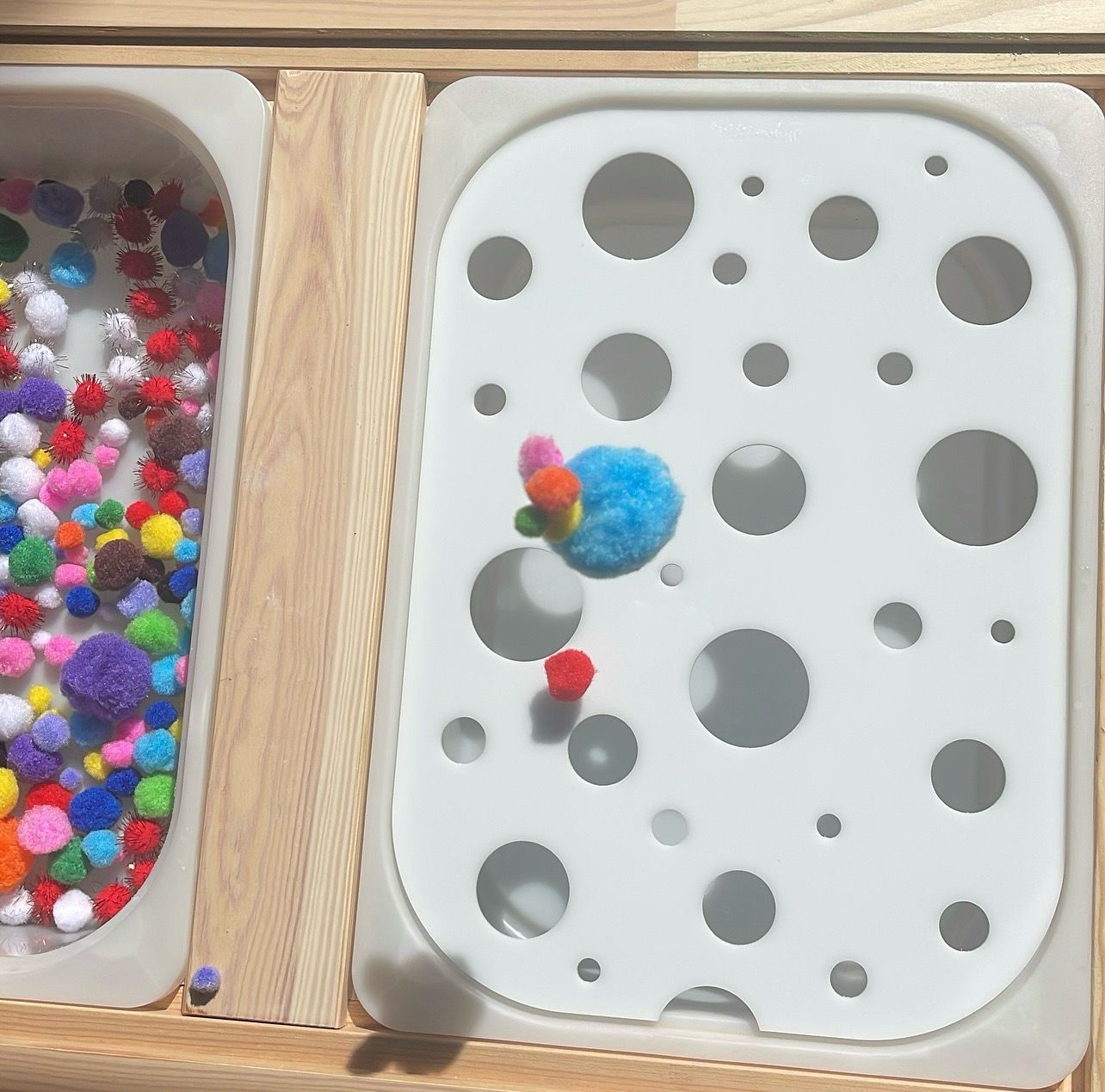 το παιδί ταξινομεί τα πομ πομ στο τραπεζάκι ικέα με τον πίνακα για κάδο trofast all your senses