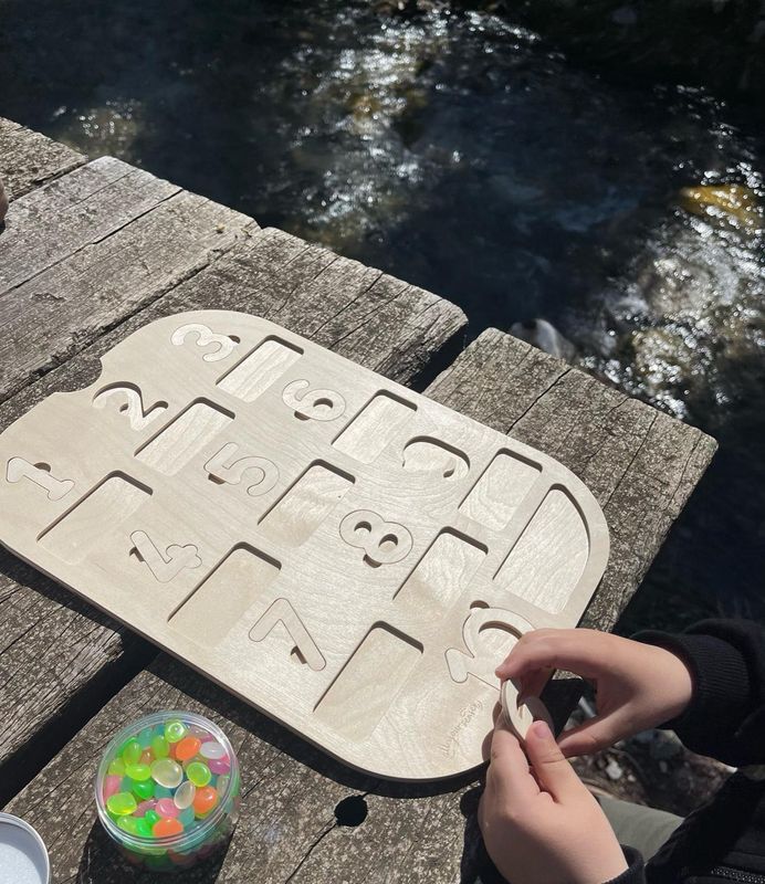 Παιδί παίζει με πίνακα αριθμών τοποθετημένο σε κάδο Trofast, δραστηριότητα Montessori με φυσικά υλικά.