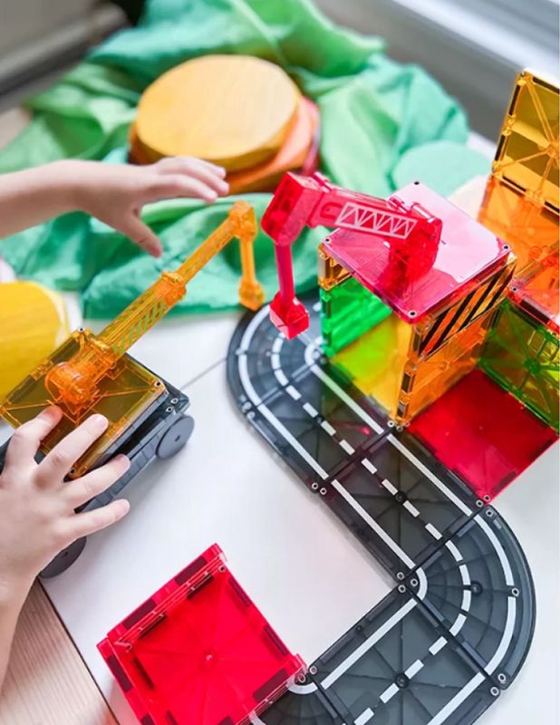 ένας μικρος μάστορας με τουβλακια, παιζει με το σετ apo magnatiles που λεγεται χτιστης