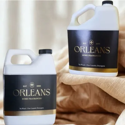 Two Orleans Nú Wash Fine Laundry detergent bottles on a beige linen background.