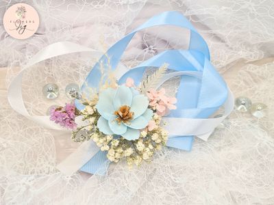 Add sophistication to your events with this handcrafted Baby Blue Cosmos corsage/boutonniere set. Made from sola wood and accented with gypsophila, fern, statice, hydrangea, and sky blue and white ribbons, ideal for weddings and proms.