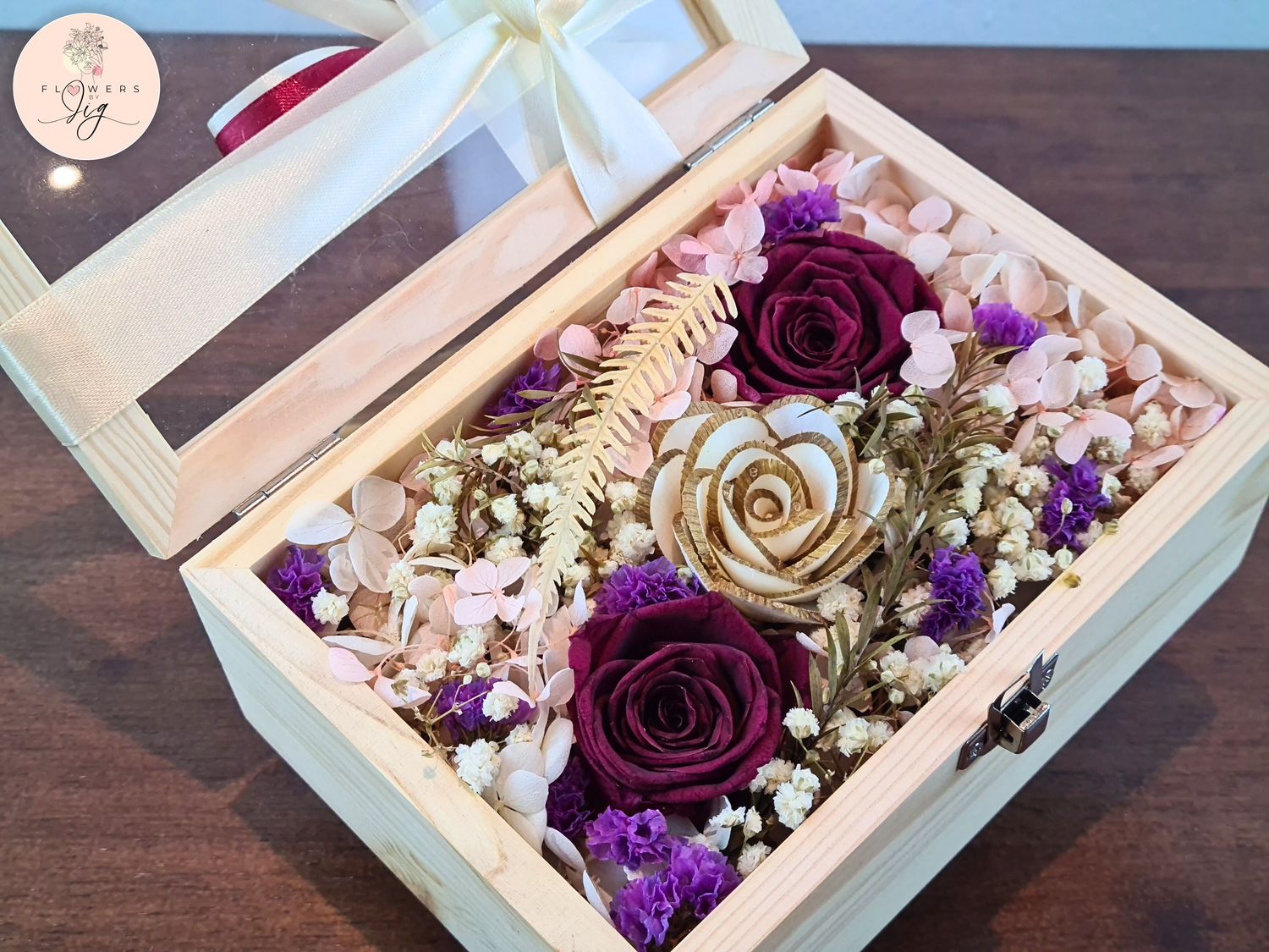 Our Pinewood Box with 2 Dark Velvet Red Infinity Roses and 1 Sola Wood Rose offers lasting beauty. Perfect for anniversaries, weddings, and birthdays. Includes dried flowers and pearls, arranged for elegance in a customizable glass box