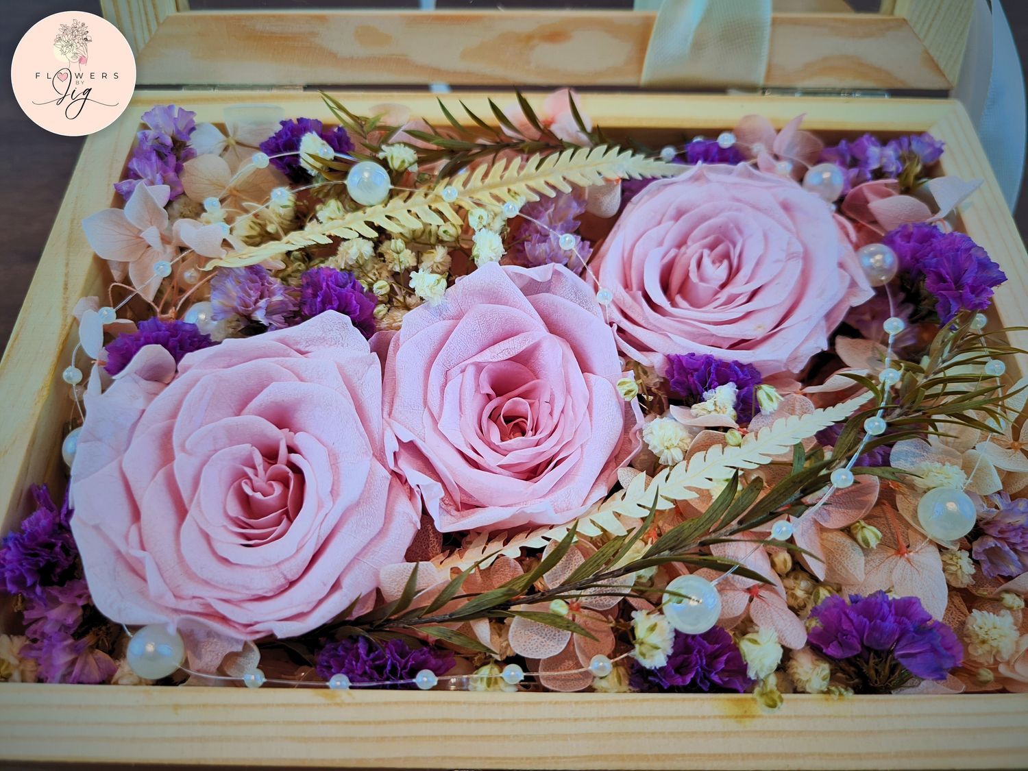 Handcrafted bouquet in a box featuring three pink infinity roses, assorted dried flowers, decorative pearls, and a customizable pinewood box with a glass cover, perfect for anniversaries, weddings, and engagements.
