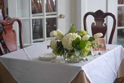 a coastal cube vase of white hydrangeas and tulips - elegant lush flowers for a wedding reception sweetheart table