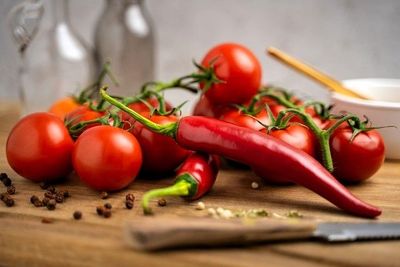 rote Tomaten, Chilischoten und Gemüsemesser auf Holzküchenarbeitsplatte