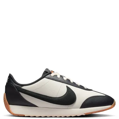 Lateral side view of Nike Women’s Pacific Leather sneaker with black Swoosh and low-profile retro silhouette.