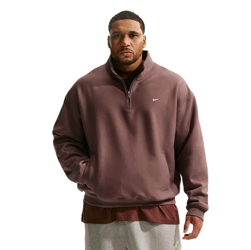 Front view of model wearing brown Nike Solo Swoosh quarter-zip fleece with half zipper and small white Swoosh