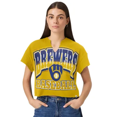 Women’s Milwaukee Brewers Galley Gold Cropped Tee With Brewers Baseball Graphic, Team Glove Logo And Notch Neckline.
