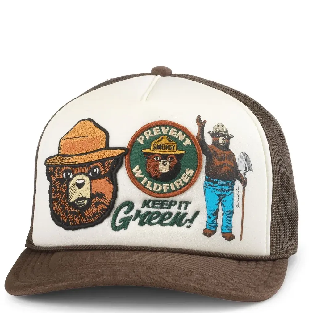 Front view of cream and brown Smokey Bear foam trucker hat with multiple vintage-style embroidered patches