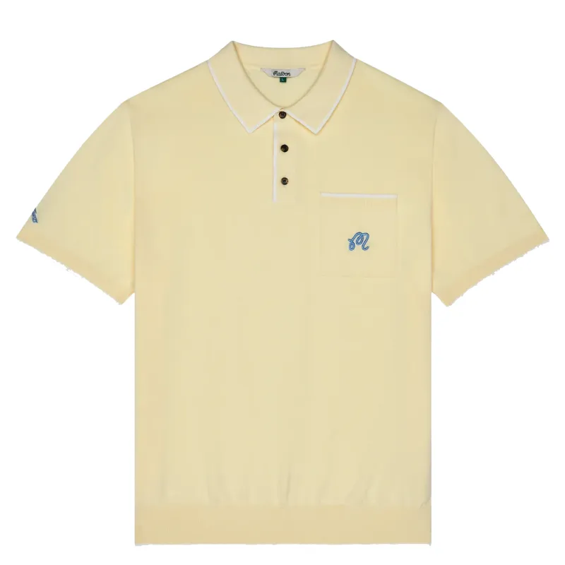 Front flat lay of soft yellow knit polo with chest pocket and embroidered logo detail