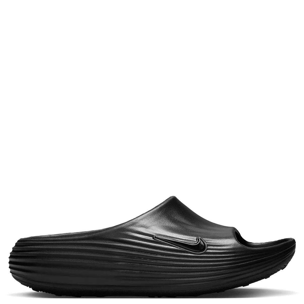 Lateral side view of black slide featuring glossy black Swoosh and textured ripple midsole design