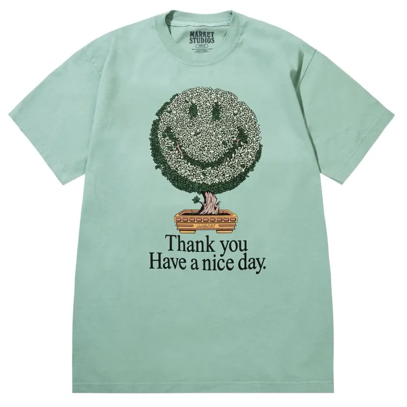 Front view of Market Studios green t-shirt with smiley bonsai tree graphic and “Thank you Have a nice day” text