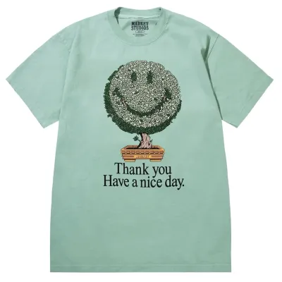 Front view of Market Studios green t-shirt with smiley bonsai tree graphic and “Thank you Have a nice day” text
