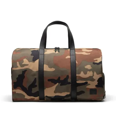Front view of Herschel Novel duffle bag in woodland camo with black handles