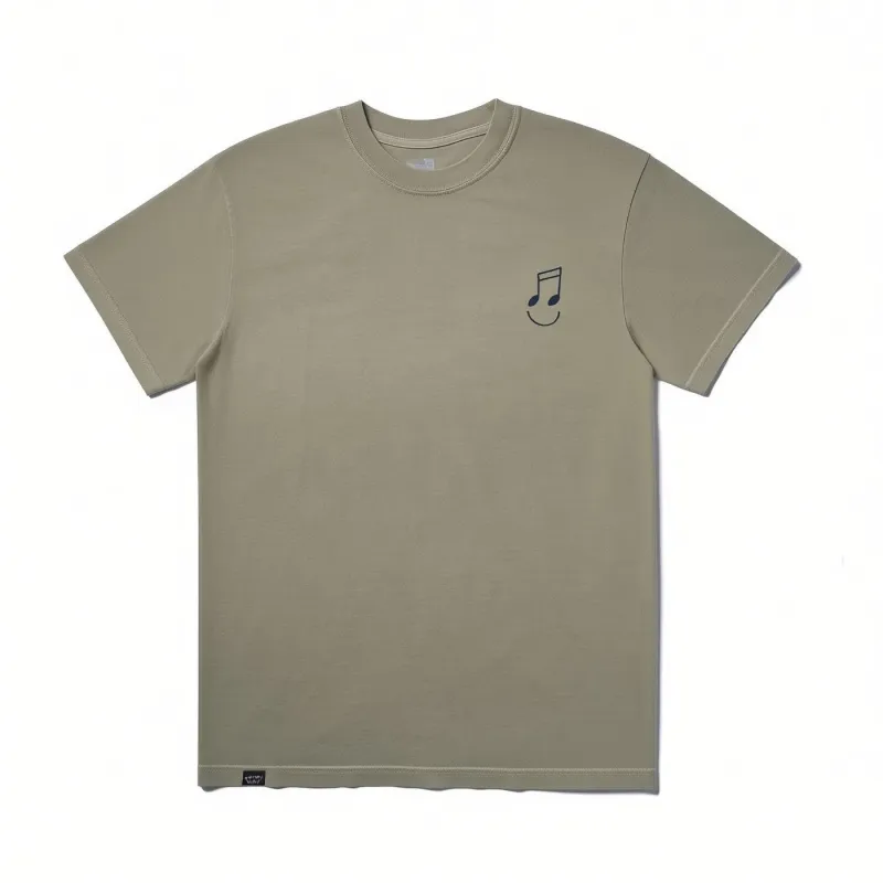 The Quiet Life Music Man Embroidered T-shirt in sage featuring a small embroidered musical note smiley graphic on the left ch