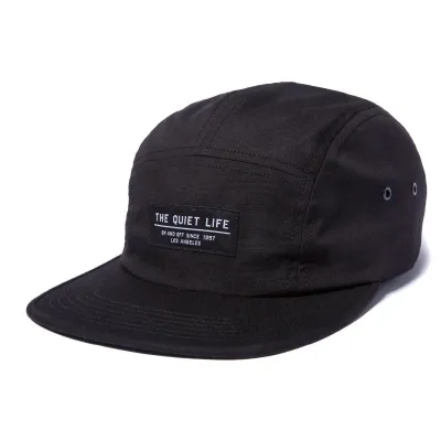 The Quiet Life Foundation 5 Panel Camper Hat in black with woven front logo label.