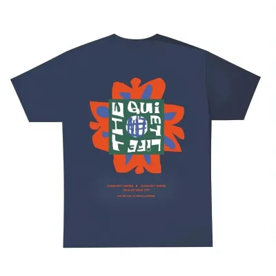 Back view of The Quiet Life Community Minded T-shirt in navy featuring large colorful graphic artwork and text print.