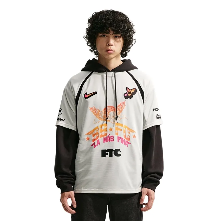 Front view of the Nike SB La Más Fina FC Soccer Jersey in Sail layered over a black hoodie.