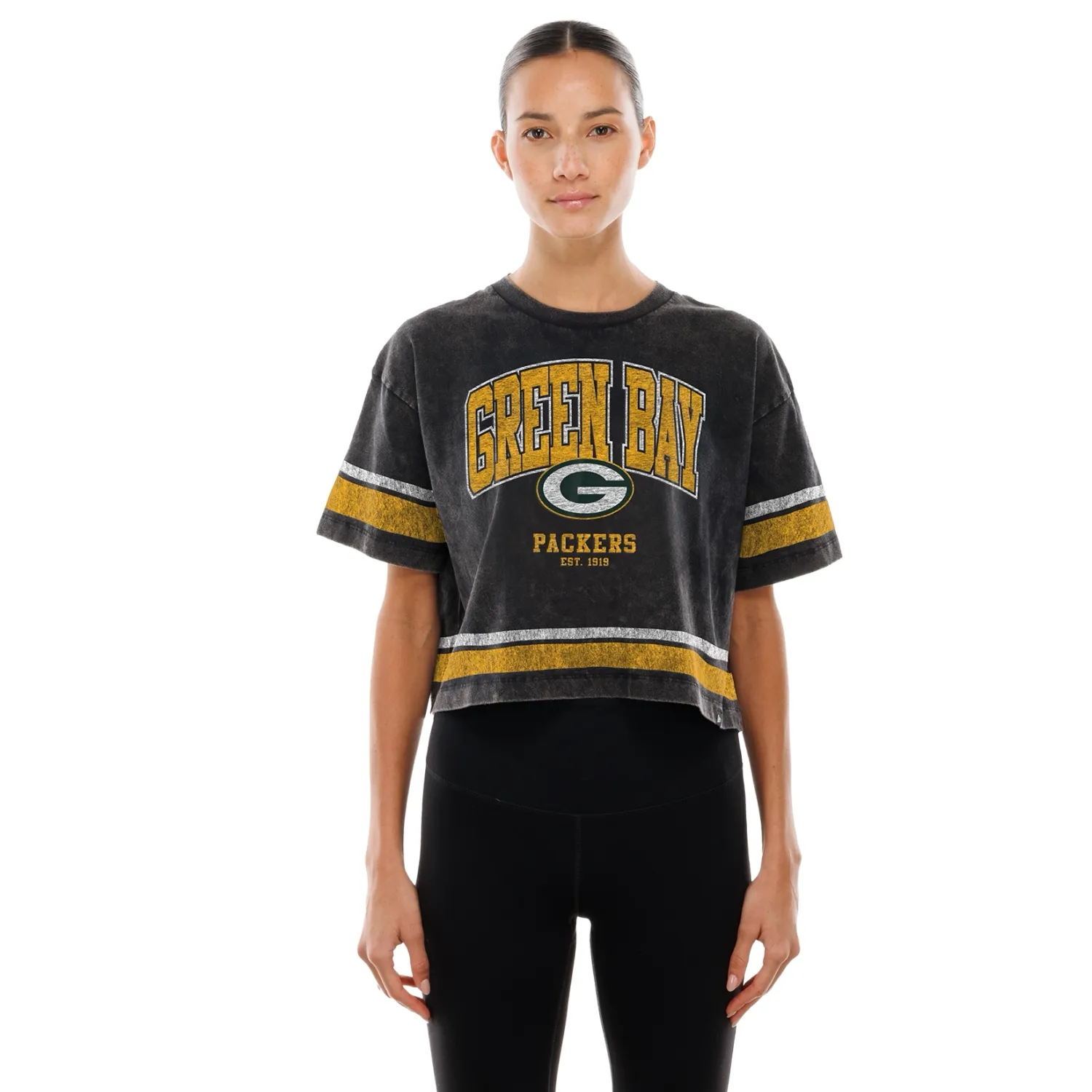 Front view of black New Era Packers women’s crop tee with varsity lettering, team logo and gold and white stripes.