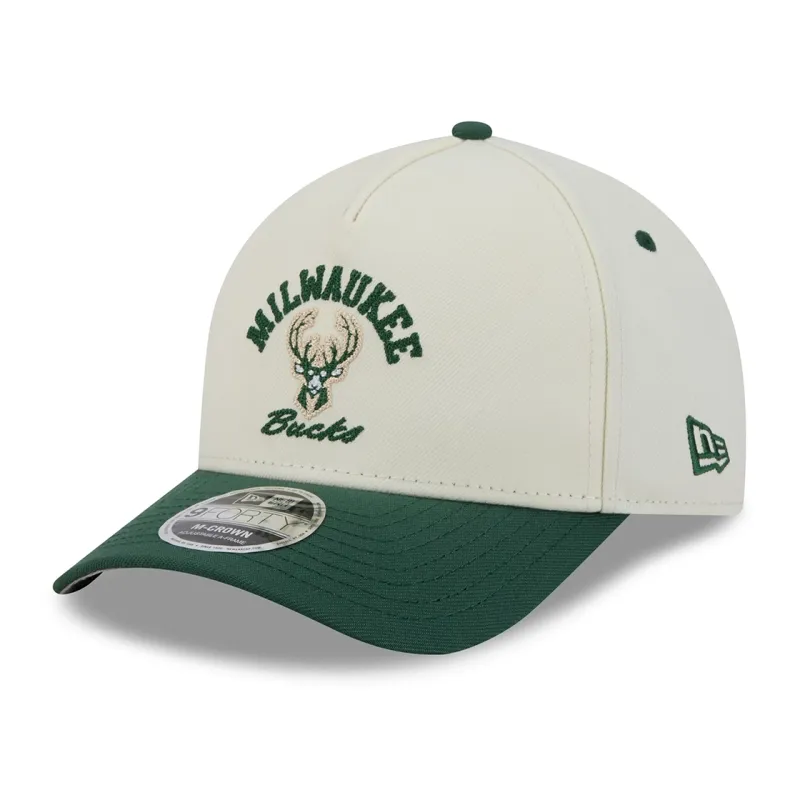 Front left angled view of cream Bucks Arch 9FORTY hat with chainstitch team graphics, green visor and New Era flag.