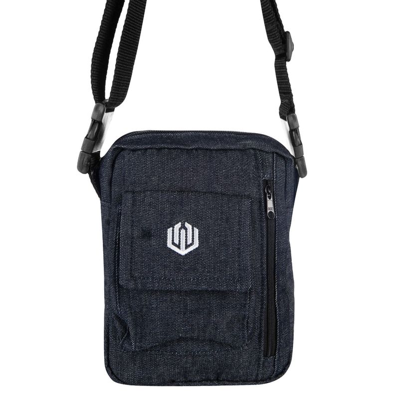 Shoulder bag de tamanho pequeno de formato levemente quadrado em jeans na cor azul escuro. Possui 3 compartimento externos, sendo 2 com fechamento em zíper e 1 estilo baggy com fecho em velcro com a logomarca da &#39;John Roger&#39; estampada em silk na cor branco, além de alça de ombro ajustável.