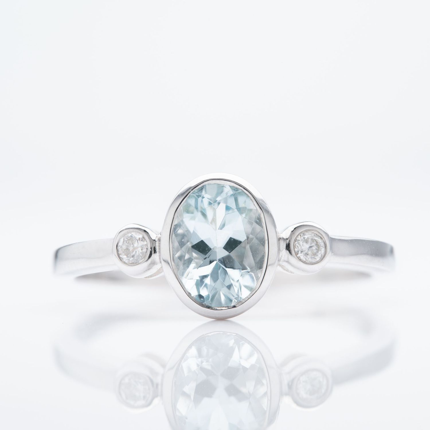9ct White Gold Oval Cut Aquamarine & Round Brilliant Cut Diamond Rubover Set Trilogy Ring