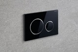 Plaque de commande Geberit Sigma20 noire avec boutons chromés brillants et garniture argentée, fixée au mur.