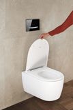 Toilettes Geberit Sigma50 avec cuvette en céramique blanche et plaque de commande murale chromée noire.