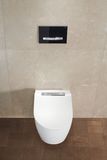 Toilettes Geberit Sigma50 avec plaque de commande noire et boutons chromés, cuvette en céramique blanche, montage mural.