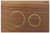 Plaque ronde Geberit Sigma50 avec anneaux en laiton brossé sur fond en noyer américain.
