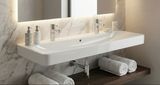 Lavabo mural carré Geberit Smyle de 120 cm en céramique blanche avec robinetterie argentée et fond en marbre.