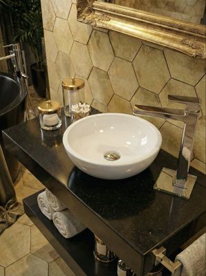 Lavabo Bolero en céramique blanche de 44 cm, matériau Marbryx, sur un plan de travail noir avec robinet argenté moderne et accents décoratifs dorés dans une salle de bains luxueuse.