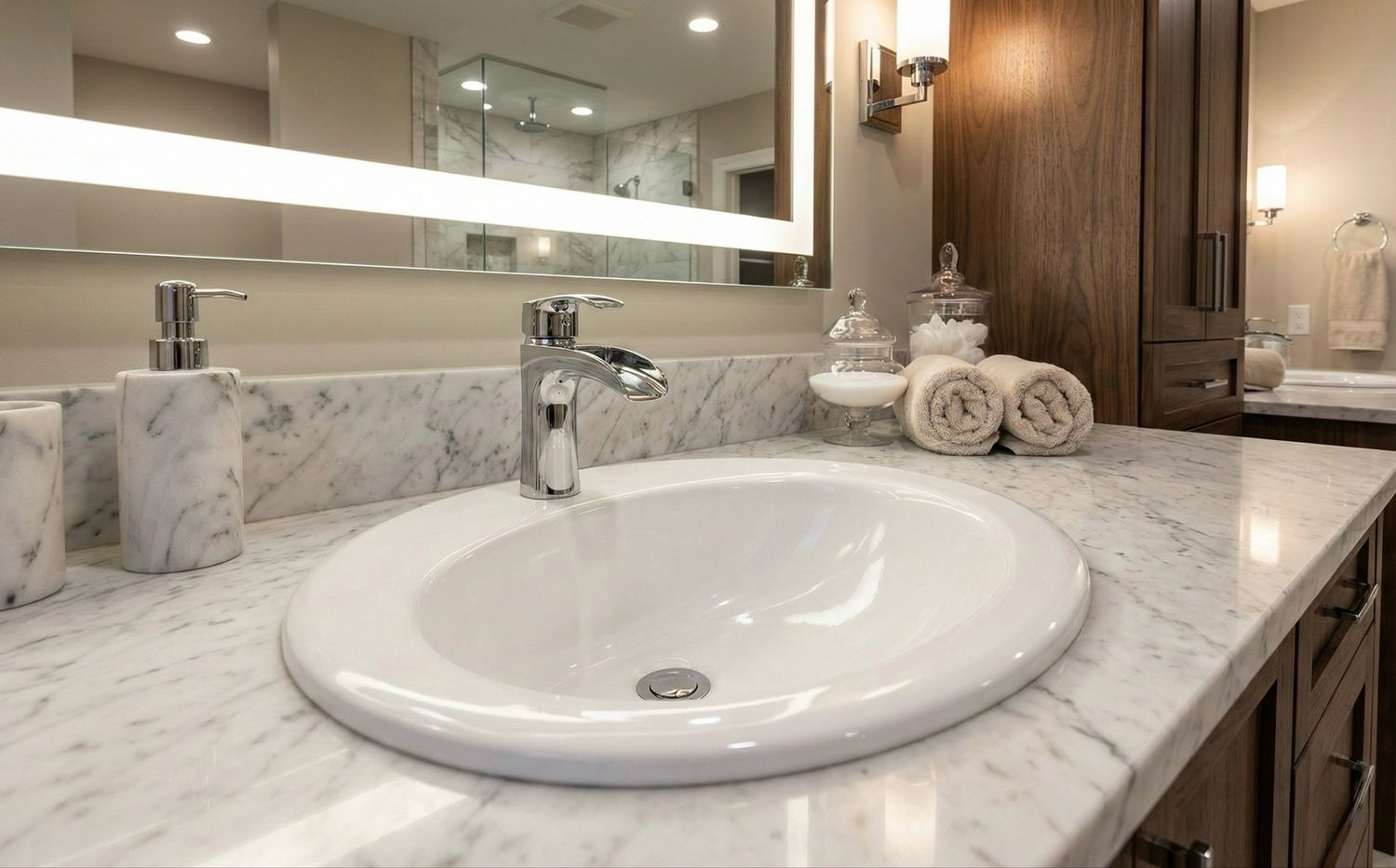 Lavabo rond blanc avec robinet argenté sur un comptoir en marbre et grand miroir.