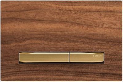 Geberit Sigma50 plaque de déclenchement laiton brossé sur fond Noyer américain.