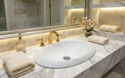 Vasque encastrable Aqua 58 cm en Marbryx blanc avec robinet doré sur comptoir en marbre.