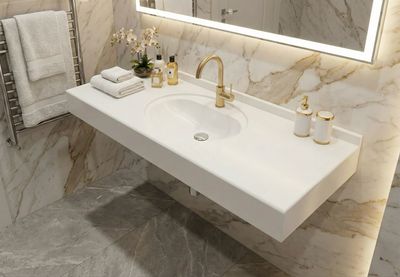 Plan-vasque Atoll Lavabo mural moderne blanc de 120 cm avec robinet doré et parois en marbre.