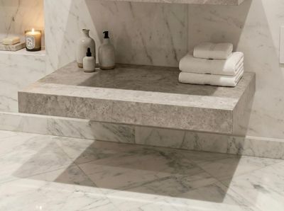 Étagère de salle de bain en marbre avec serviettes blanches et articles de toilette sur une surface en marbre gris, finition Kedhel gris.